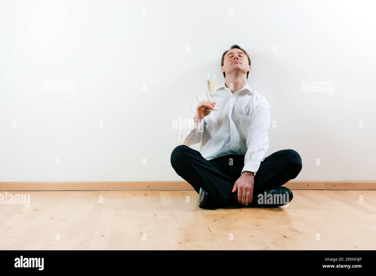 Man sitting cross-legged on the wooden floor of his apartment Stock ...