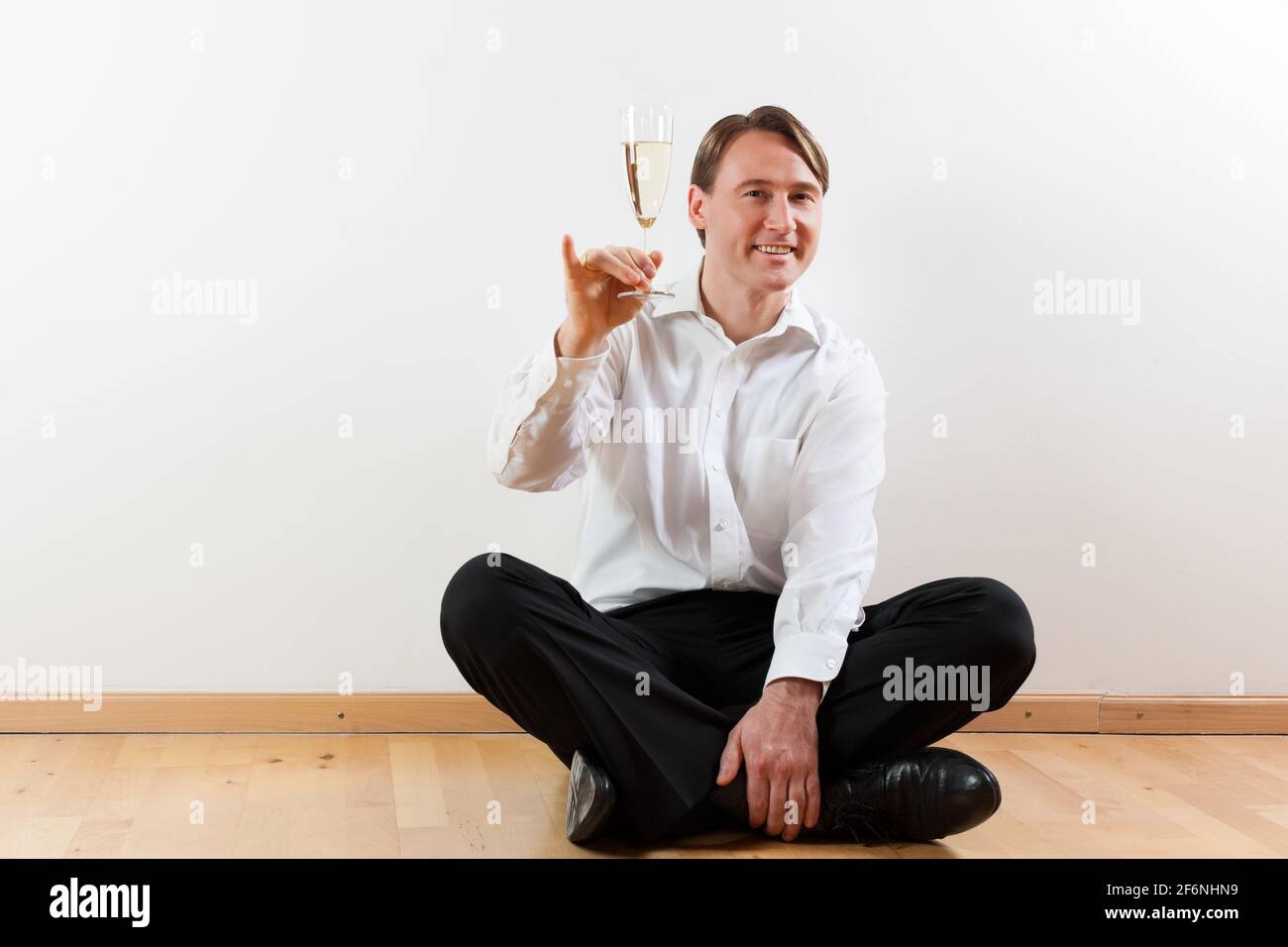 Man sitting cross-legged on the wooden floor of his apartment Stock ...