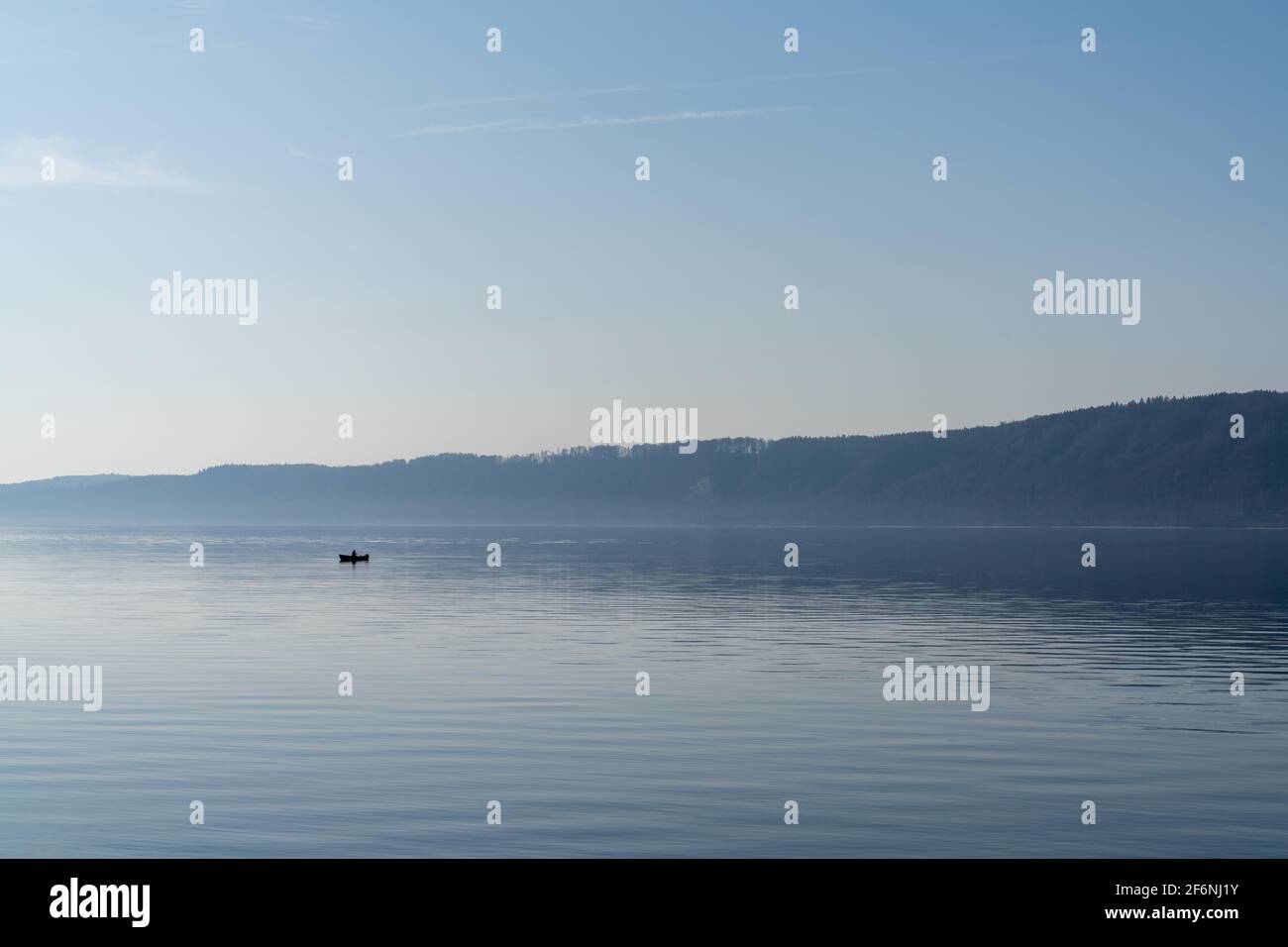 A view of a calm blue lake with a small motorboat cruising through the water Stock Photo