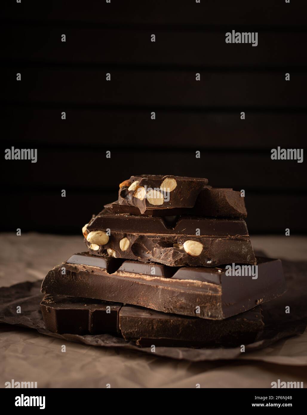 Dark chocolate with almonds and hazelnuts in a stack on brown background Stock Photo