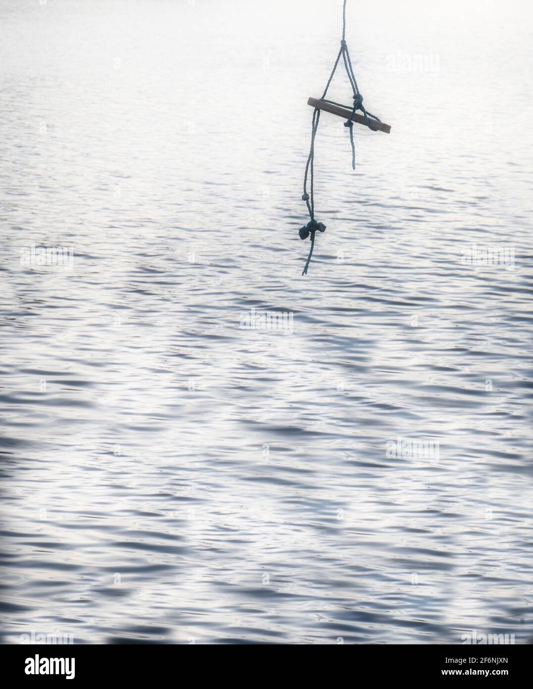 Rope swing hanging above water. Concept of carefree, freedom, escapism, tranquility Stock Photo