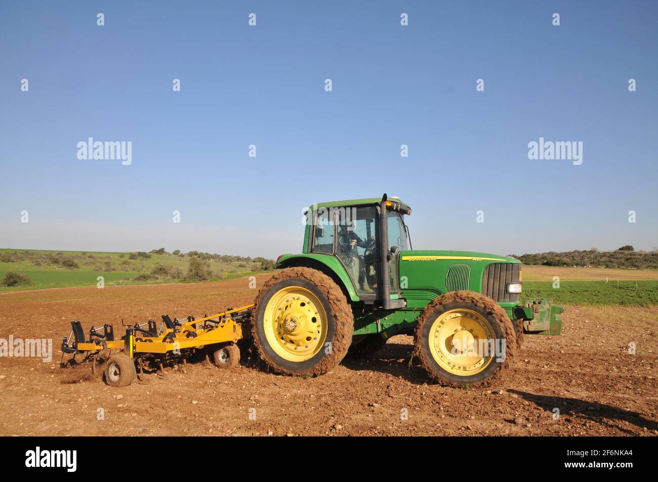 Farmer drives a cultivator to till the earth before planting or sowing. A cultivator is any of several types of farm implement used for secondary till Stock Photo