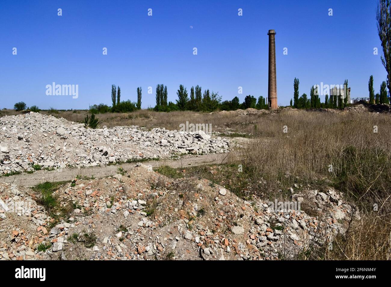 Ruins of an abandoned demolished old plant with high rise chimney. Ruined factory in  Ukraine Stock Photo