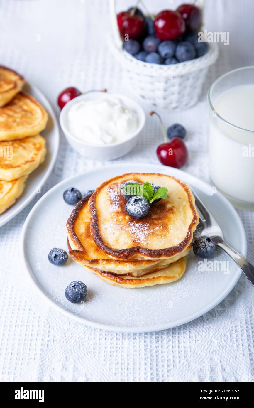 Cottage cheese pancakes (syrniki). Homemade cheesecakes from cottage cheese with sour cream, berries and milk. Traditional Russian dish. Close-up. Stock Photo