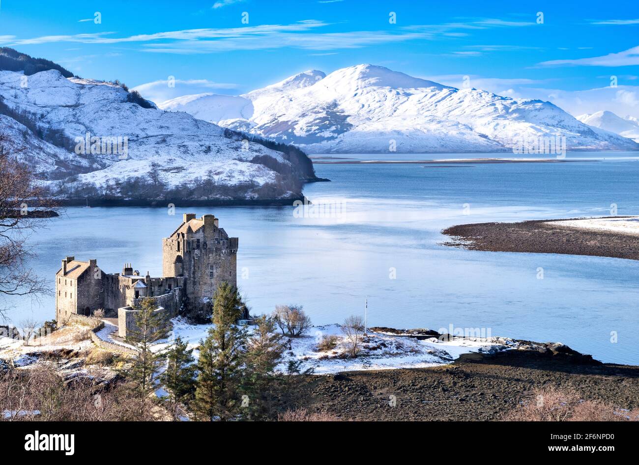 EILEAN DONAN CASTLE LOCH DUICH HIGHLAND SCOTLAND A BLUE SKY THE CASTLE IN WINTER  HEAVY FALL OF SNOW ON THE  HILLS Stock Photo