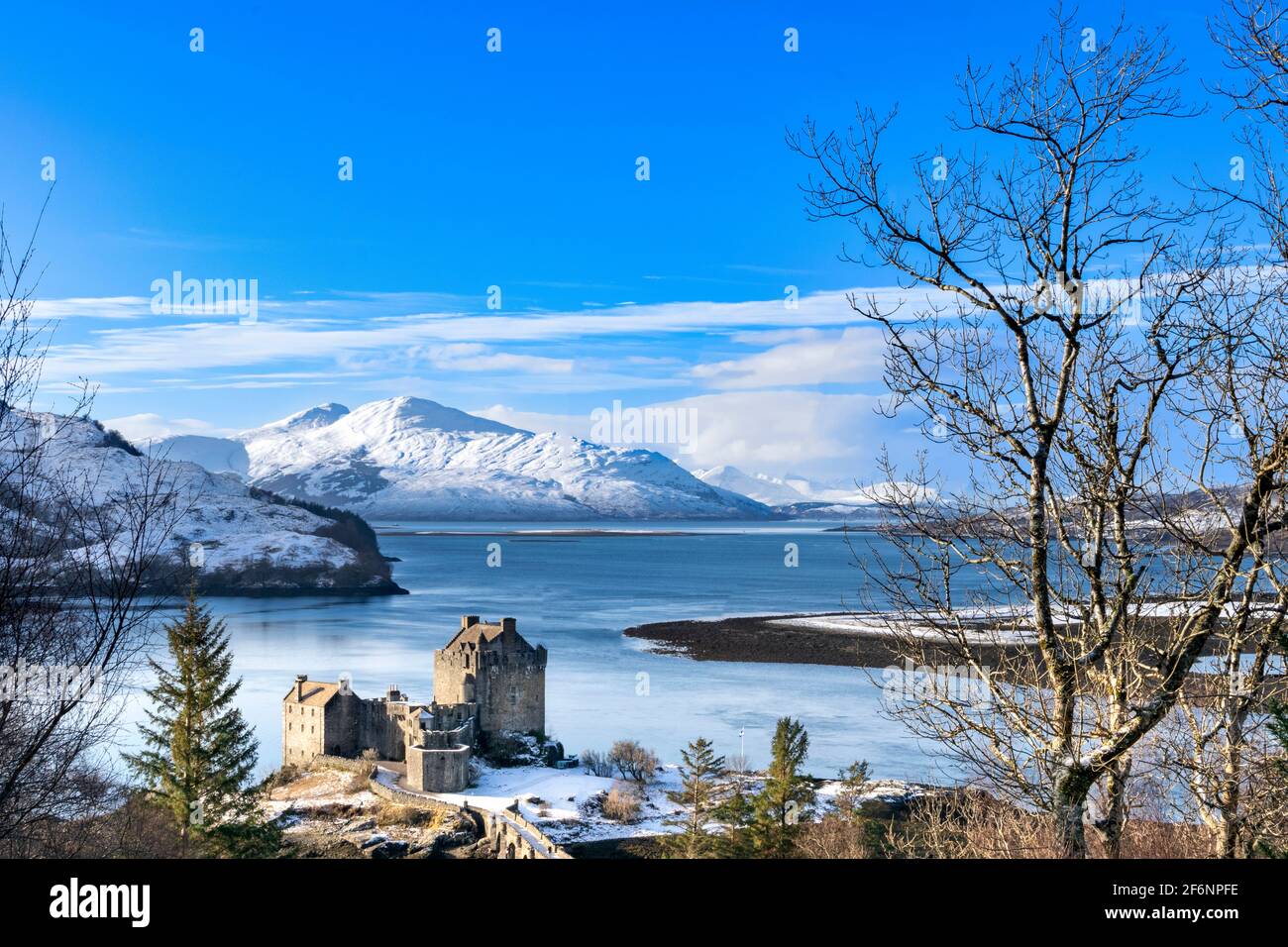 EILEAN DONAN CASTLE LOCH DUICH HIGHLAND SCOTLAND A BLUE SKY THE CASTLE IN WINTER  WITH A HEAVY FALL OF SNOW ON THE  HILLS Stock Photo