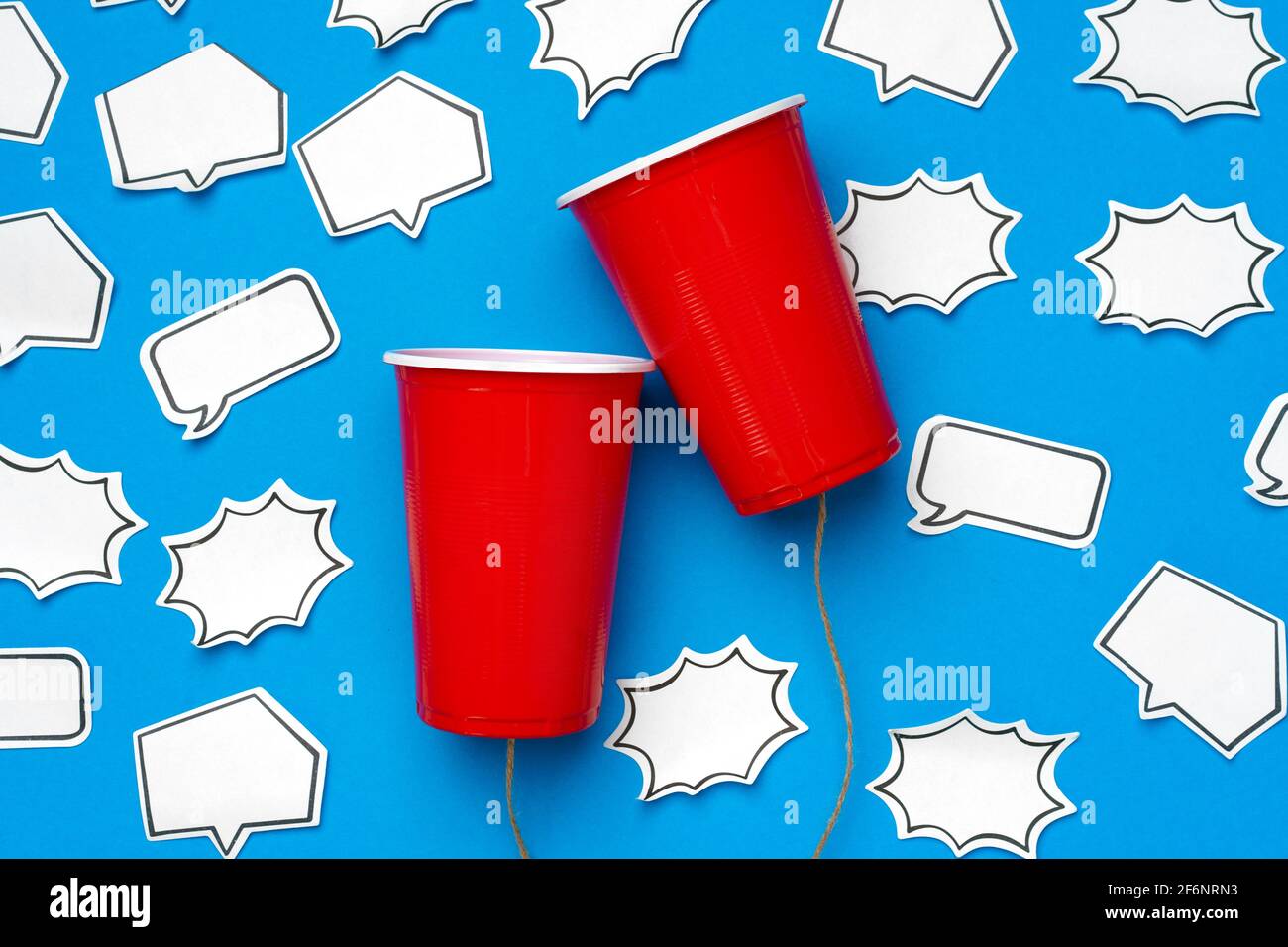 Two red cups connected with a thread with speech bubbles on blue ...