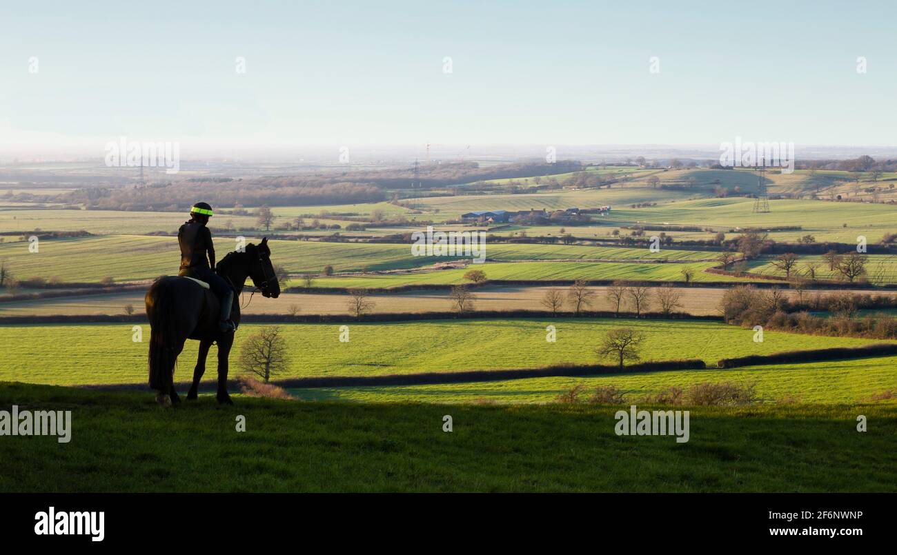 AYLESBURY, UK - December 13, 2014. Woman riding horse in landscape, horseback riding on a hill overlooking Aylesbury Vale, Buckinghamshire, UK Stock Photo