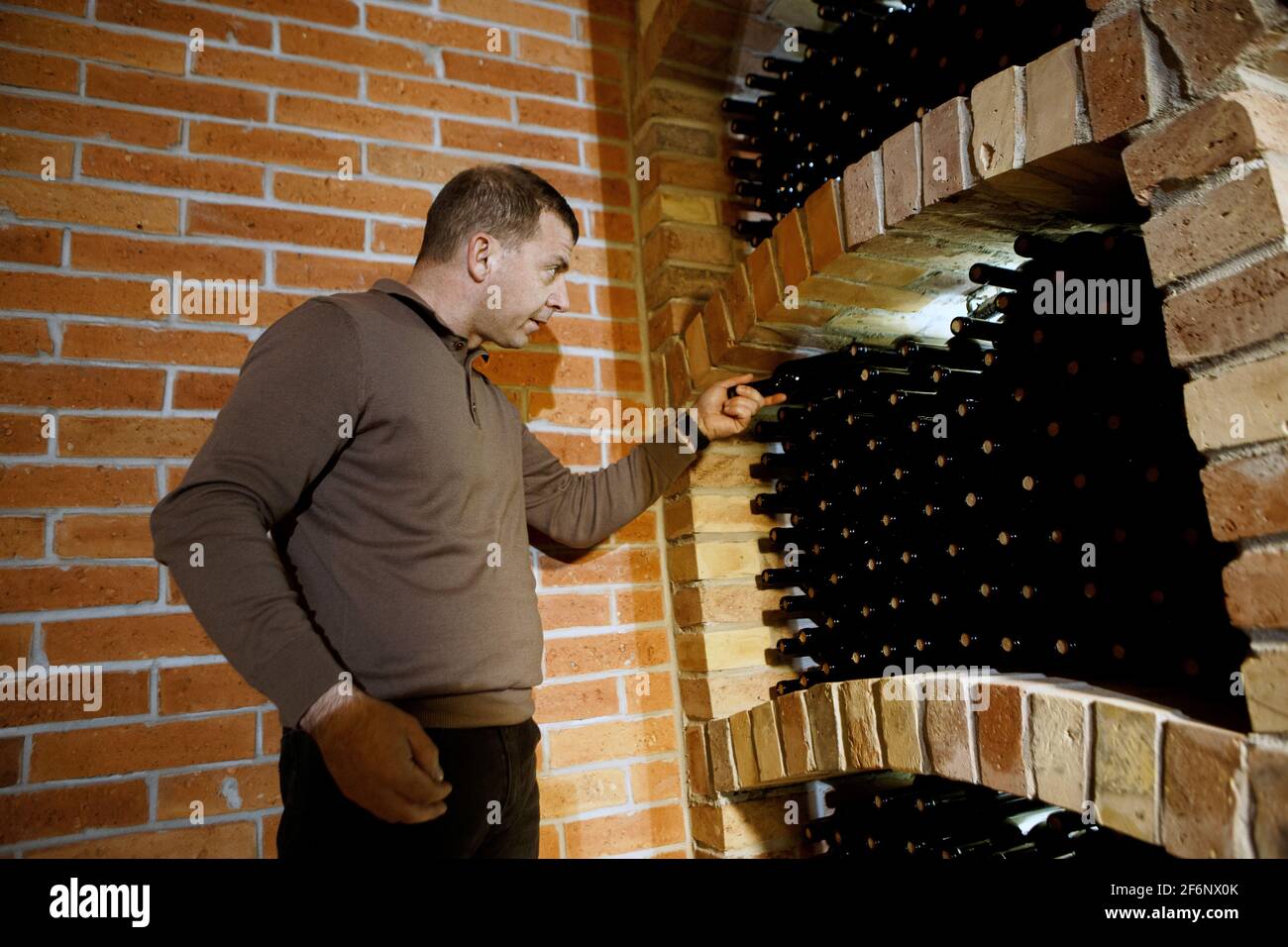 BEREHOVE, UKRAINE - MARCH 25, 2021 - Chief winemaker Zoltan Udvargeli picks up a bottle of wine in a new wine cellar at Chateau Chizay set up for agei Stock Photo