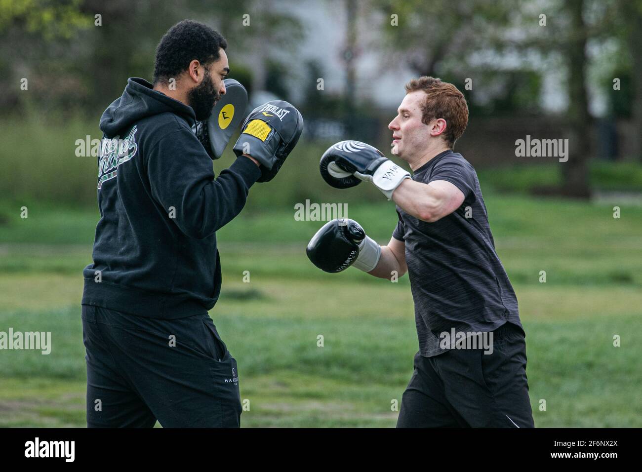 WIMBLEDON LONDON, UK 2 April 2021. Two men sparring with boxing gloves on an overcast day on Wimbledon Common as lockdown restrictions are lifted. A cold spell is  forecast  over the Easter weekend in London with  a drop in temperatures following unseasonably warm temperatures. Credit amer ghazzal/Alamy Live News Stock Photo
