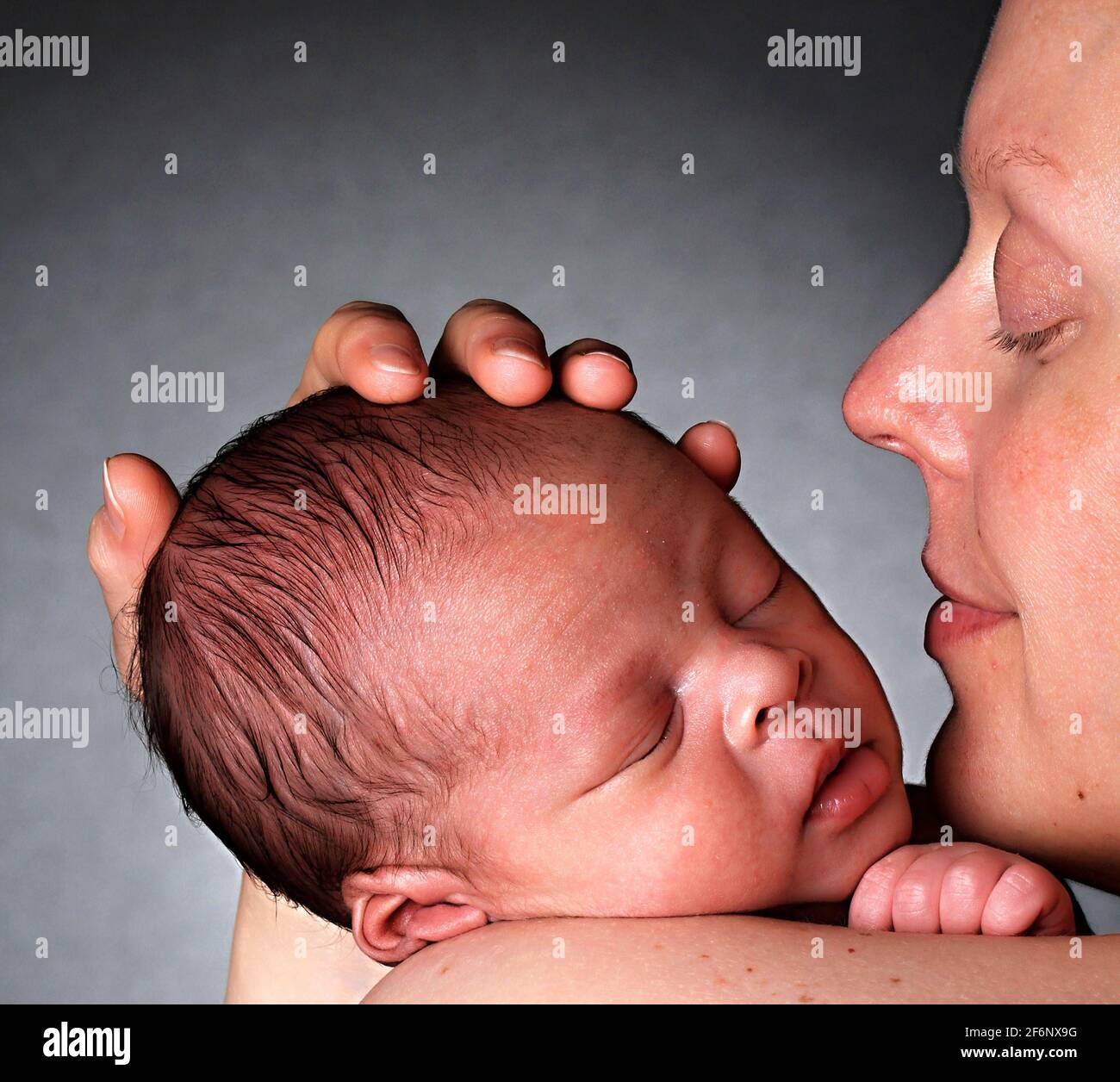 baby in mother's arms and wrapped up in white blanket just been cared for after having a good sleep in bed stock photograph stock photo Stock Photo