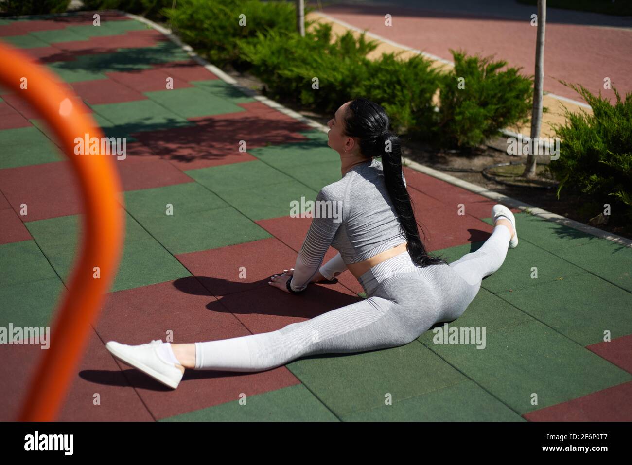 Young sporty woman in a tracksuit sitting on the sports playground and ...