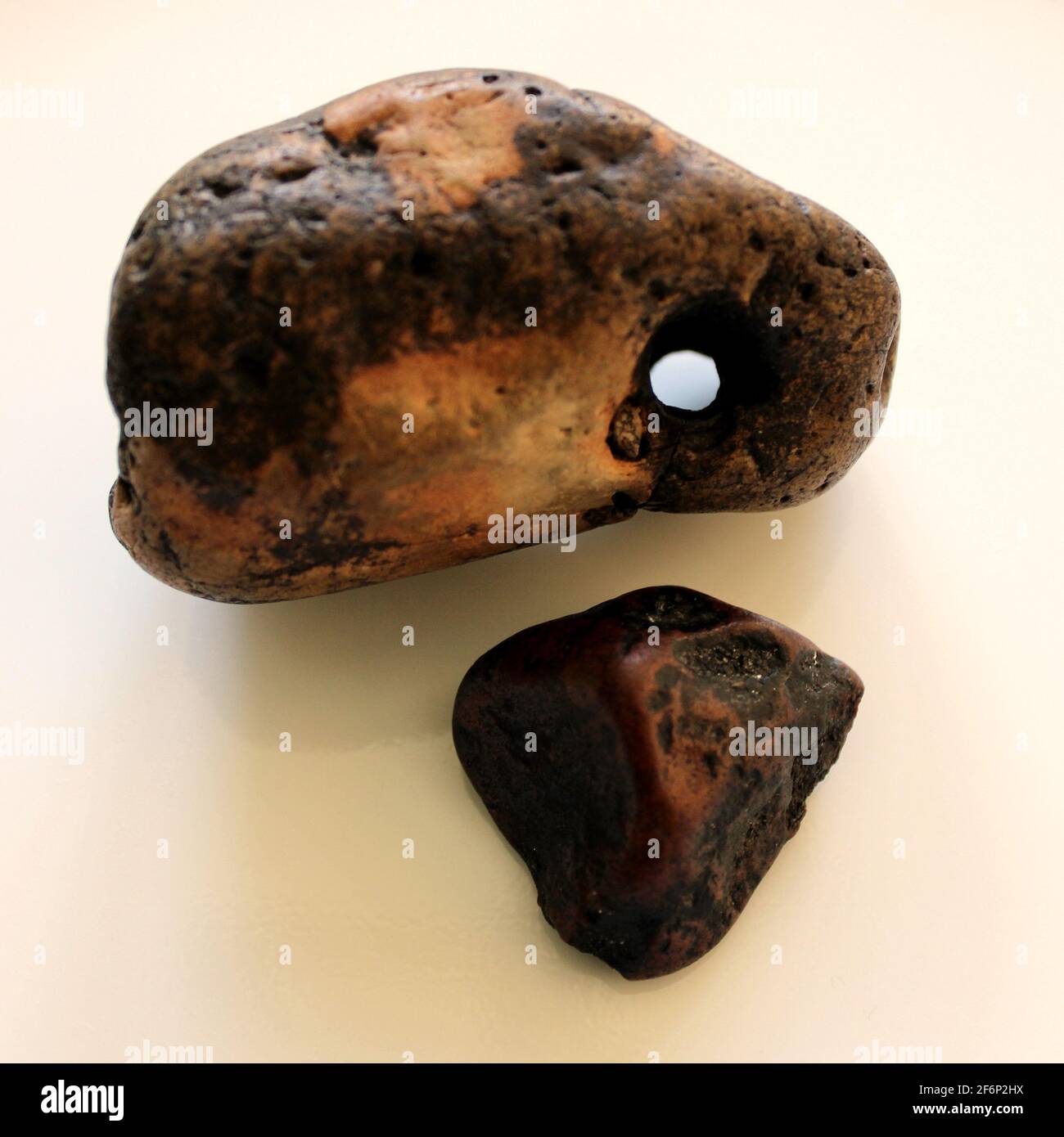 mottled holed stone and very dark red jasper pebble Stock Photo