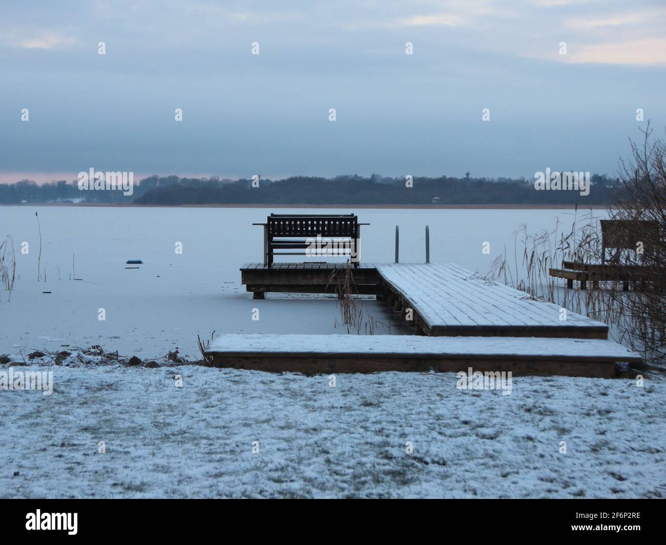Bathing Pier with Bench in winter morning in Winter Snow at Frozen Lake Stock Photo