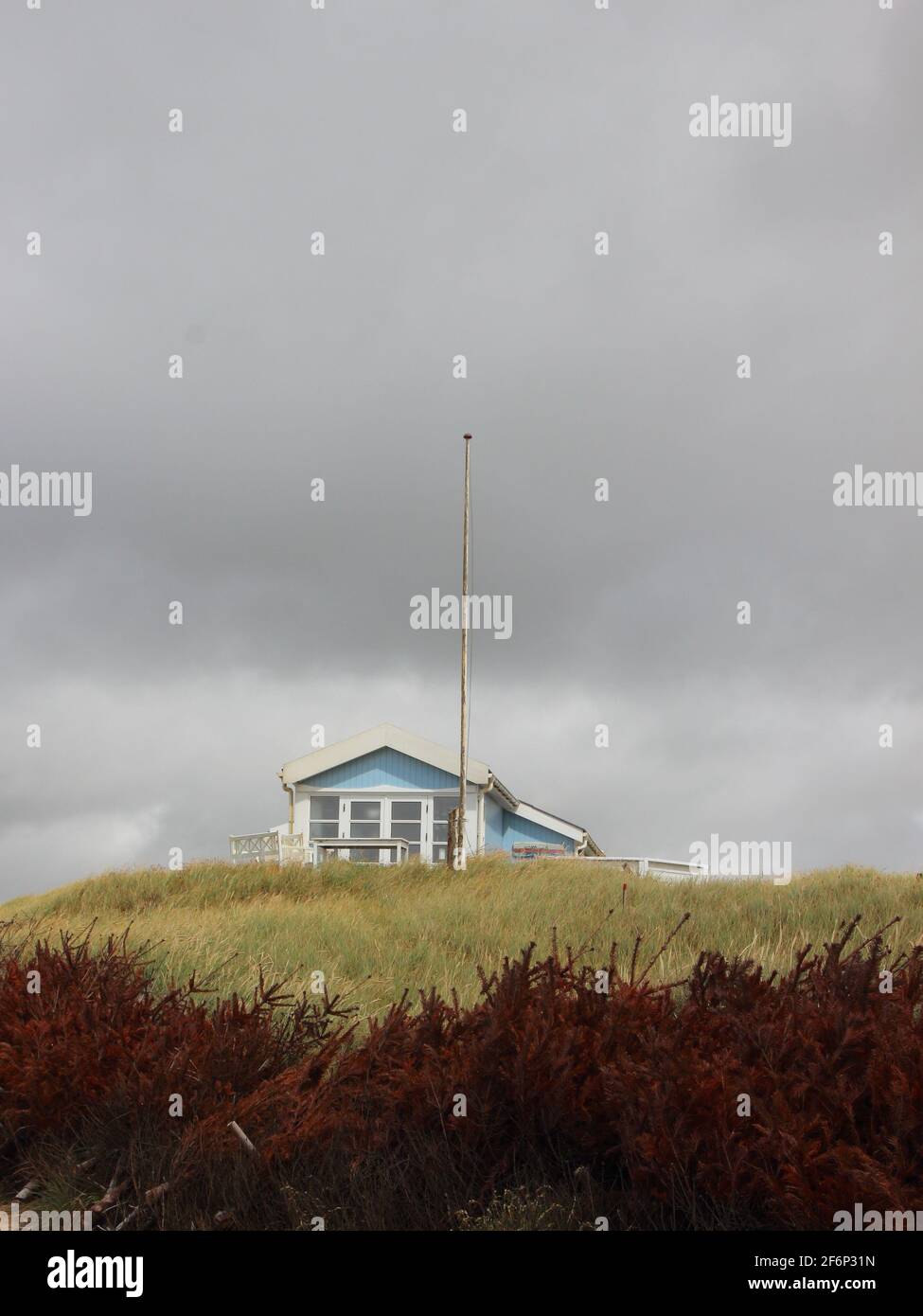 Blue Summerhouse on green Hill with Flagpole in front Stock Photo