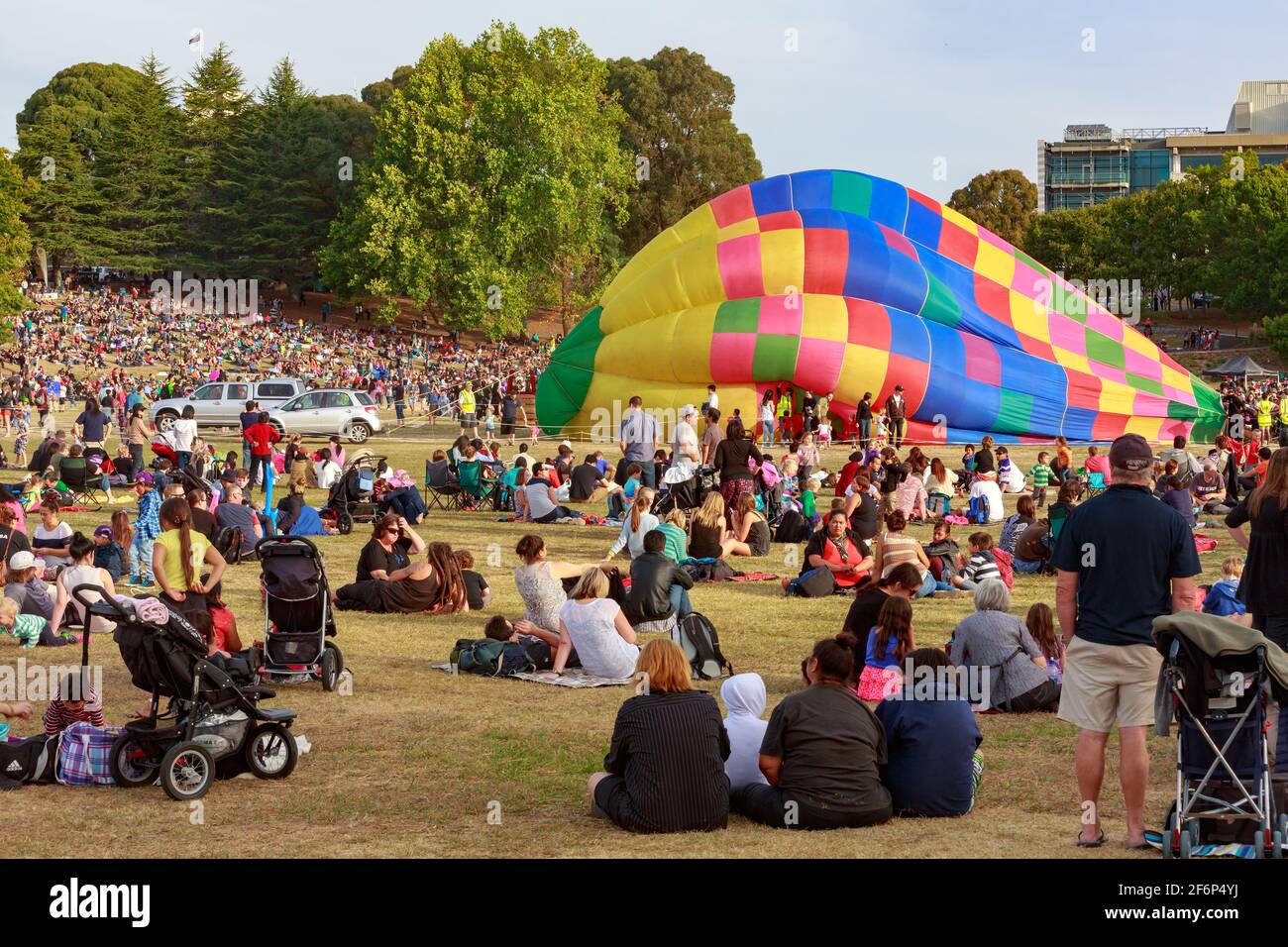 A partially inflated hot air balloon in the middle of a large crowd
