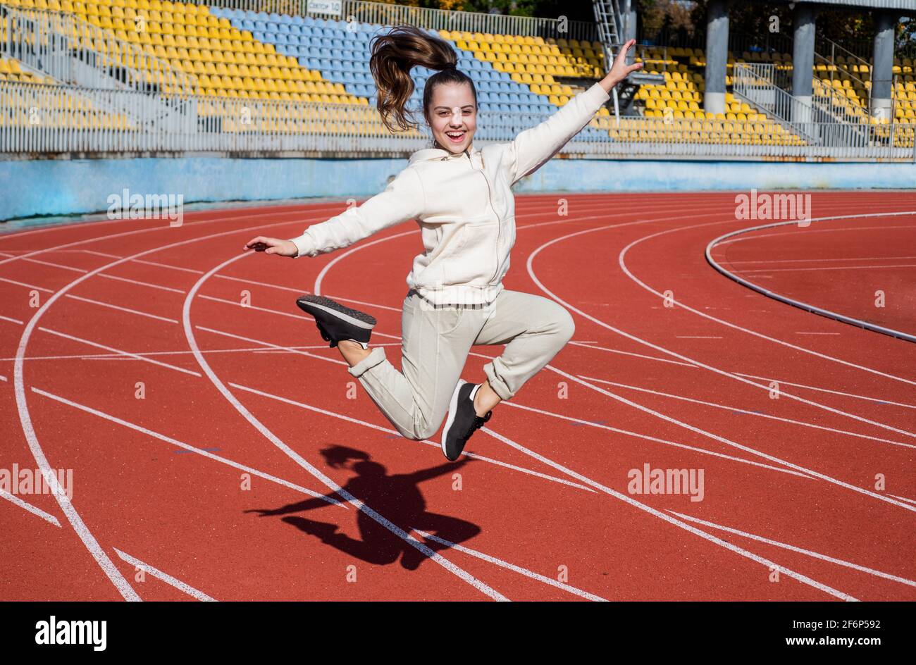 Energetic girl child jump at athletics track physical education