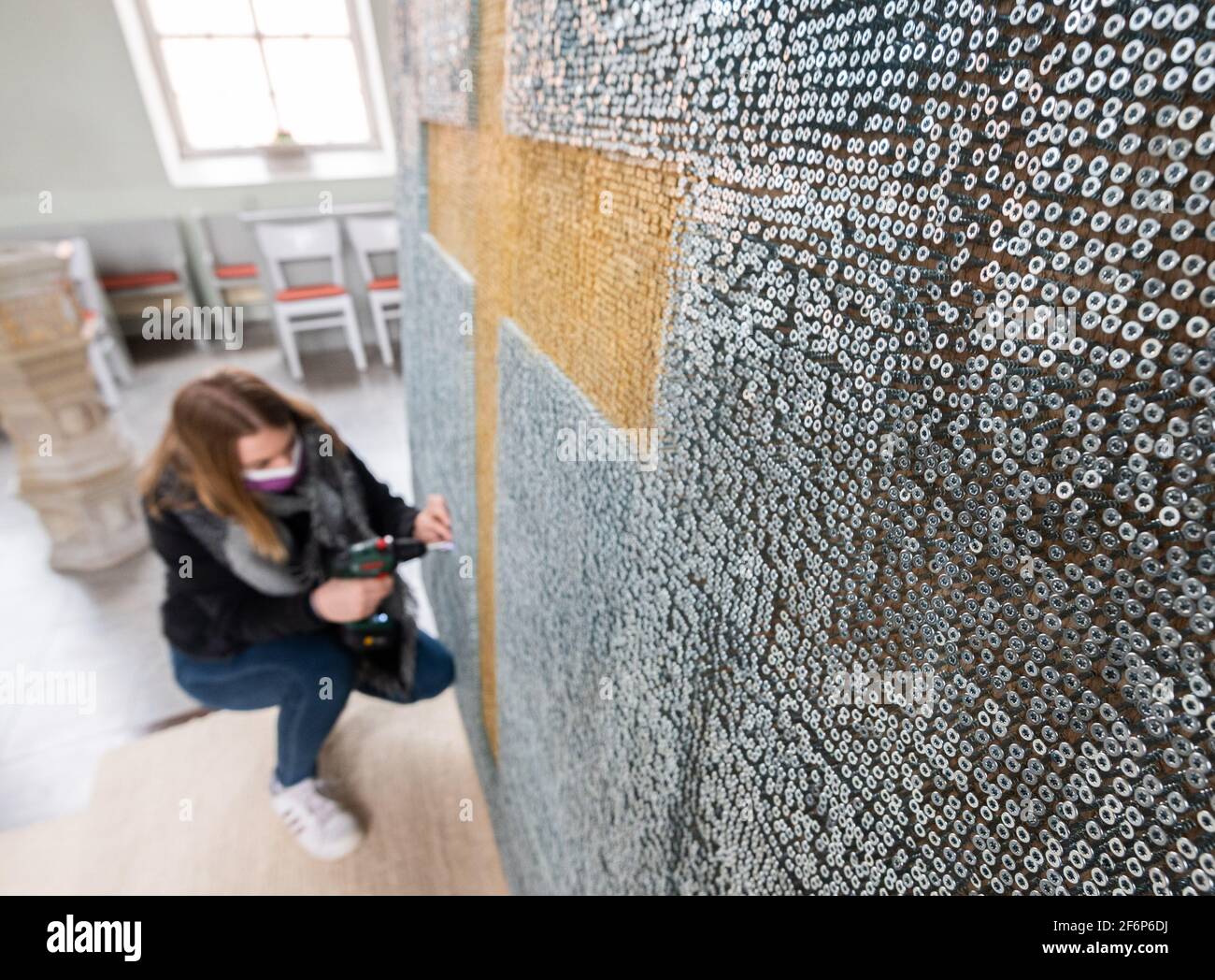 Eime, Germany. 02nd Apr, 2021. Michelle squats with a cordless screwdriver on a cross made of screws in the church in Deinsen in the Eime district of Hildesheim on Good Friday. Confirmation students, young people and Pastor Stefanie Radtke in the Protestant parish have built a cross in memory of the Corona dead with a cross made of almost 76,000 screws. According to the Robert Koch Institute (RKI), more than 76,000 people in Germany have died from or with a Corona infection. Credit: Julian Stratenschulte/dpa/Alamy Live News Stock Photo