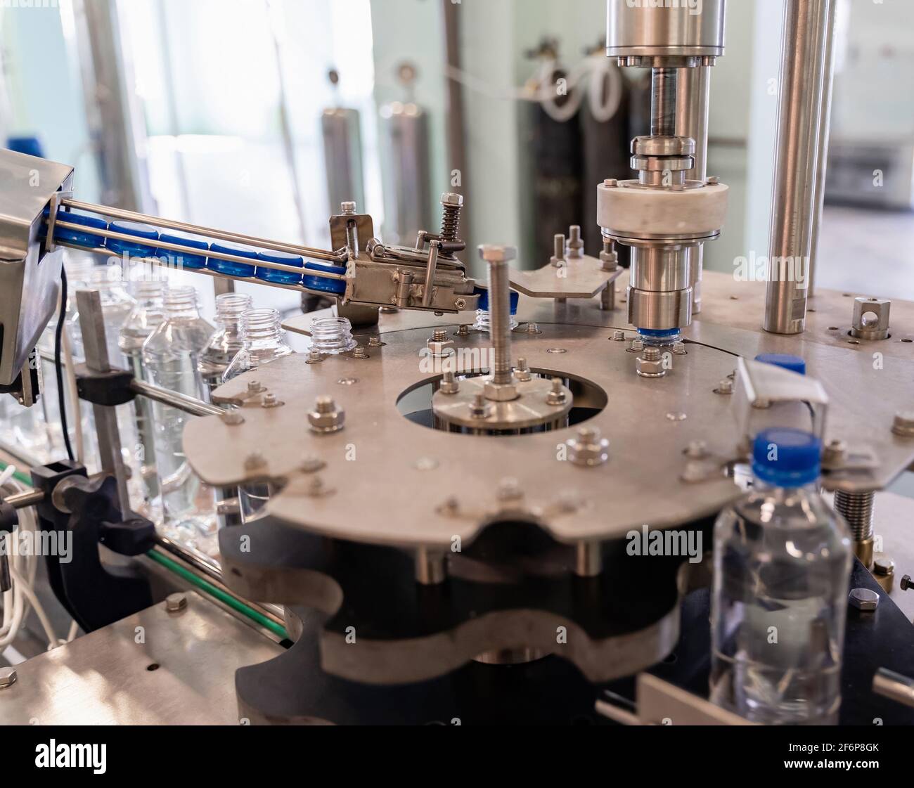 Process of twisting the lids on plastic bottles. Water production line. Stock Photo