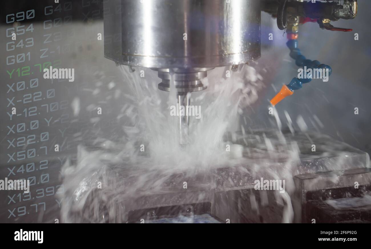 CNC milling machine cutting workpiece with coolant. CNC programming