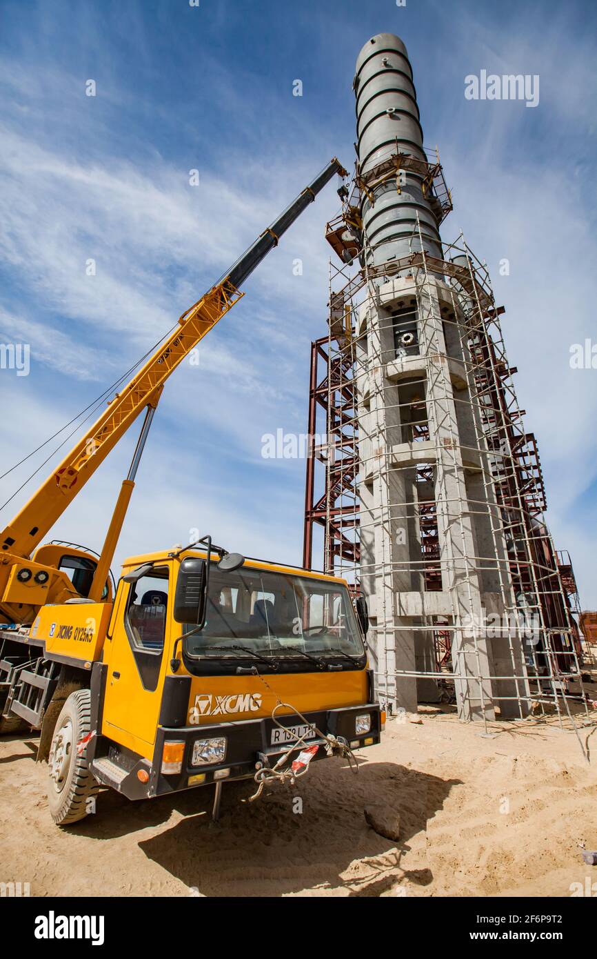 Aktau, Kazakhstan - May 19, 2012: Construction of asphaltic bitumen plant refinery column. Metal distillation tower and hydraulic hoist. Stock Photo