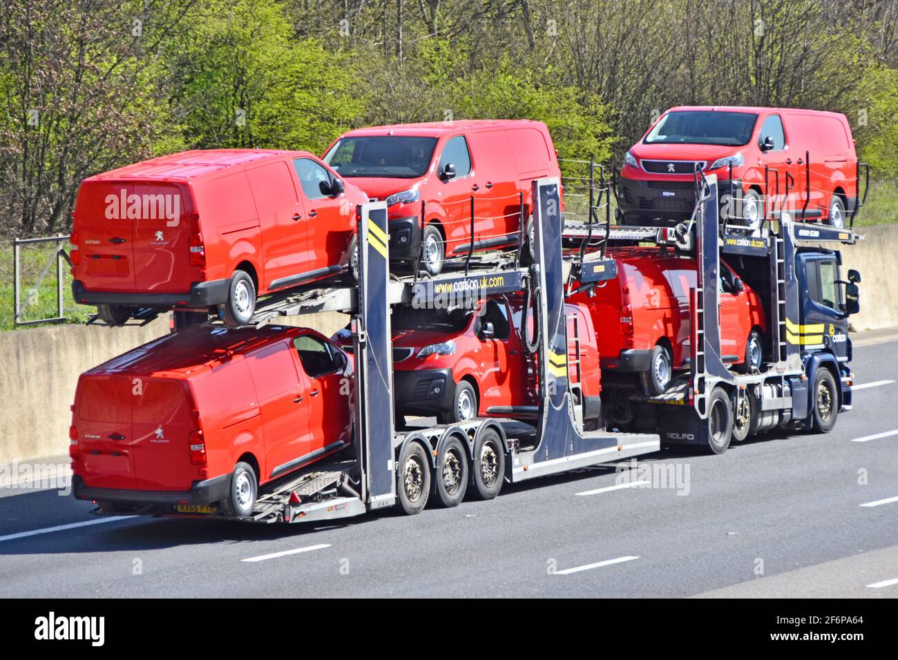 Loaded lorry truck car distribution transporter trailer to transport & deliver six new red Peugeot Expert brand of vans driving on motorway England UK Stock Photo