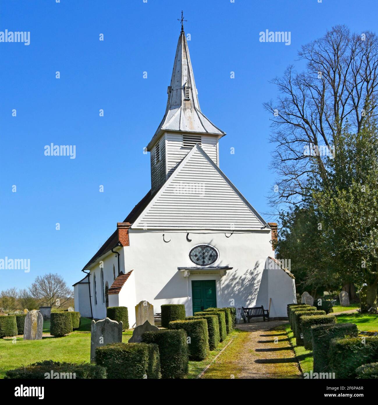 Old historical 12th century ancient medieval grade II listed Lambourne parish church building yew hedge topiary path bell tower spire Abridge Essex UK Stock Photo