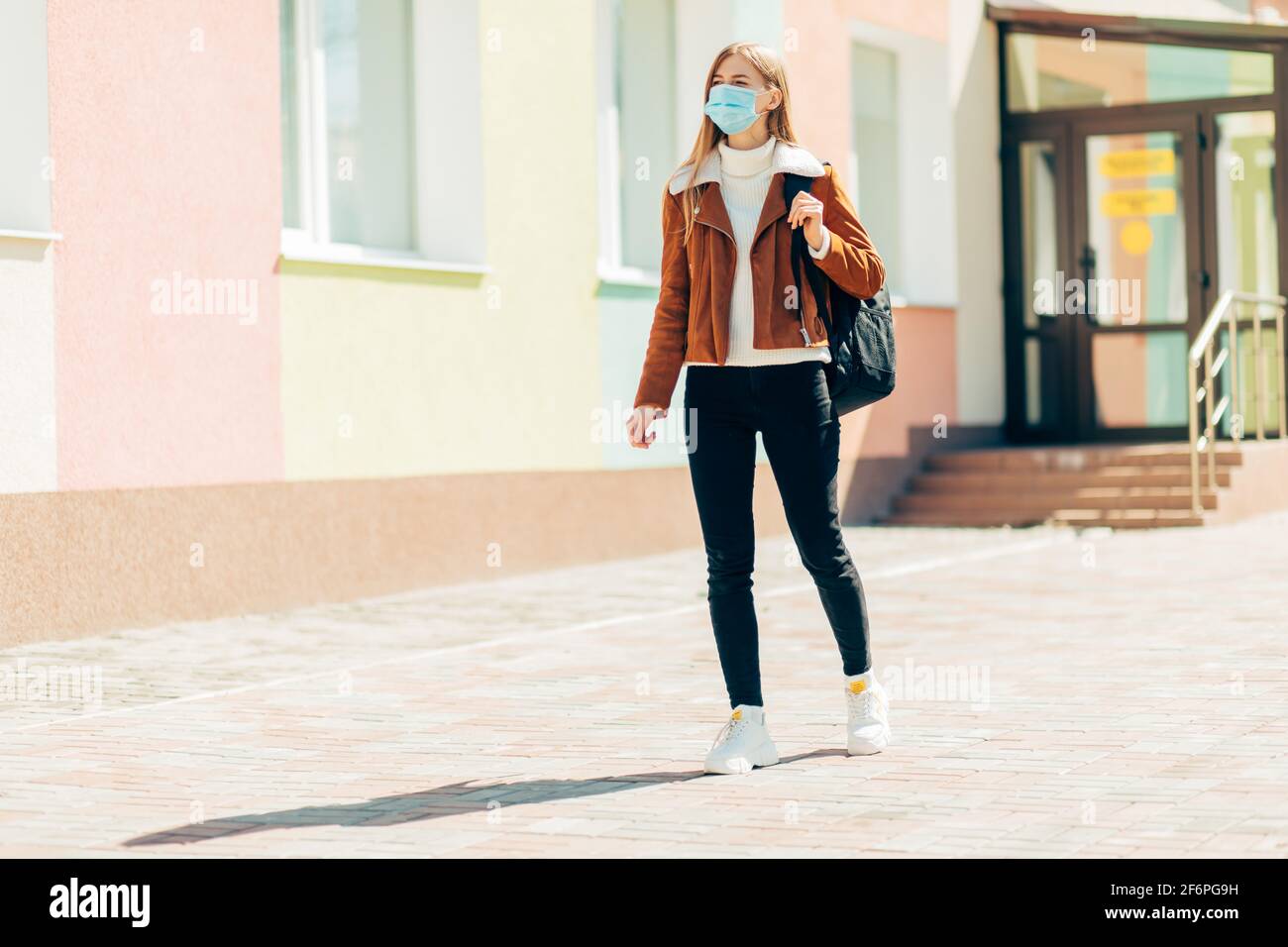 Young woman on a city street wearing a mask protecting from the spread ...