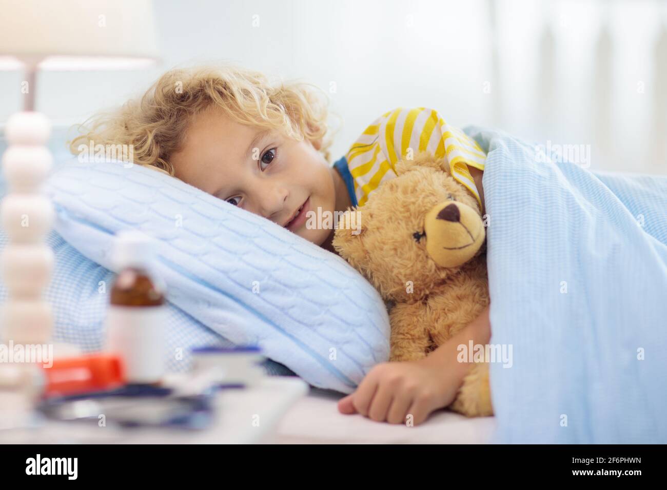 Sick little boy with asthma medicine. Ill child lying in bed. Unwell