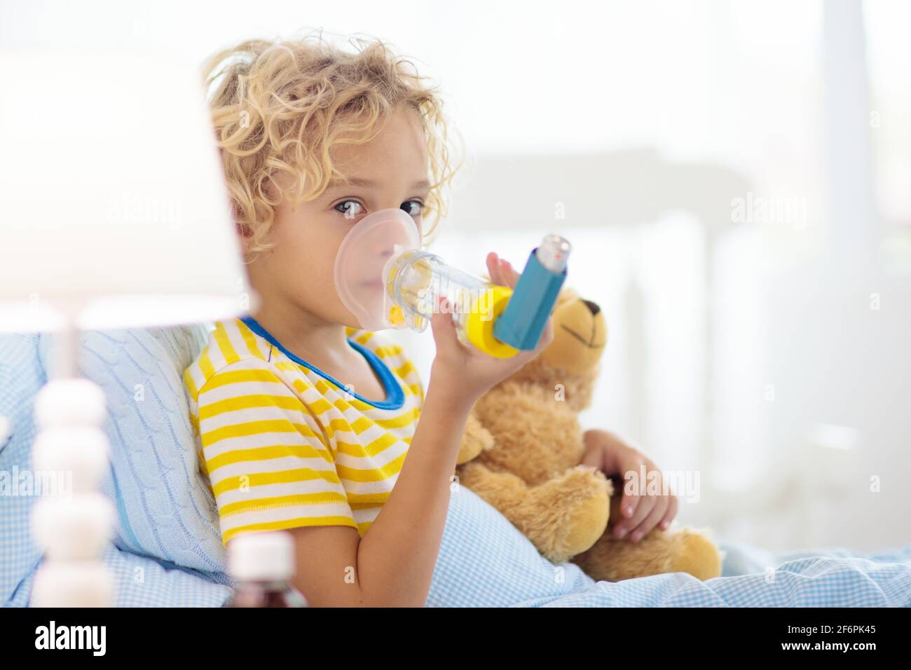 Sick little boy with asthma medicine. Ill child lying in bed. Unwell