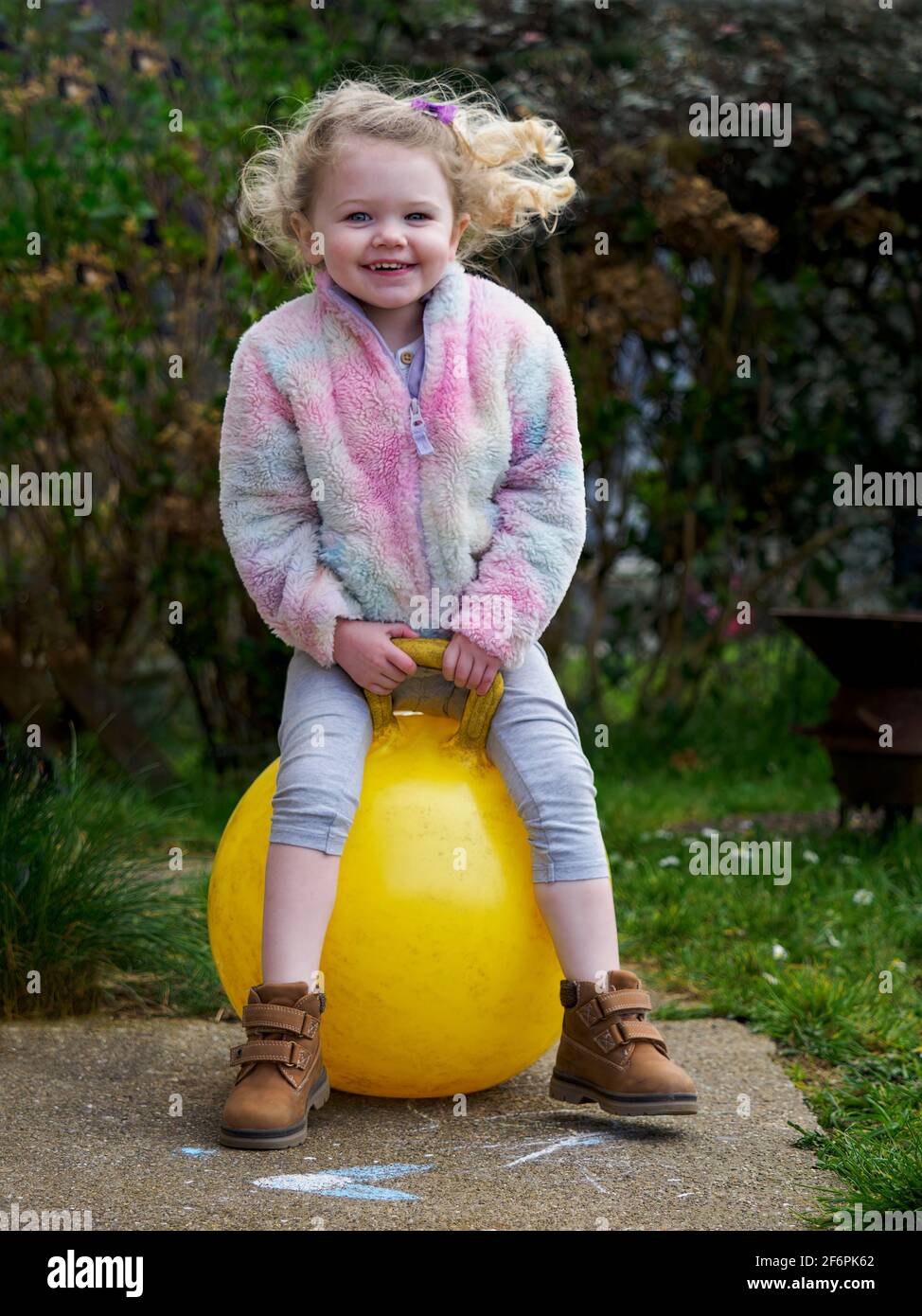 Young girl playing with a space hopper in spring, UK Stock Photo
