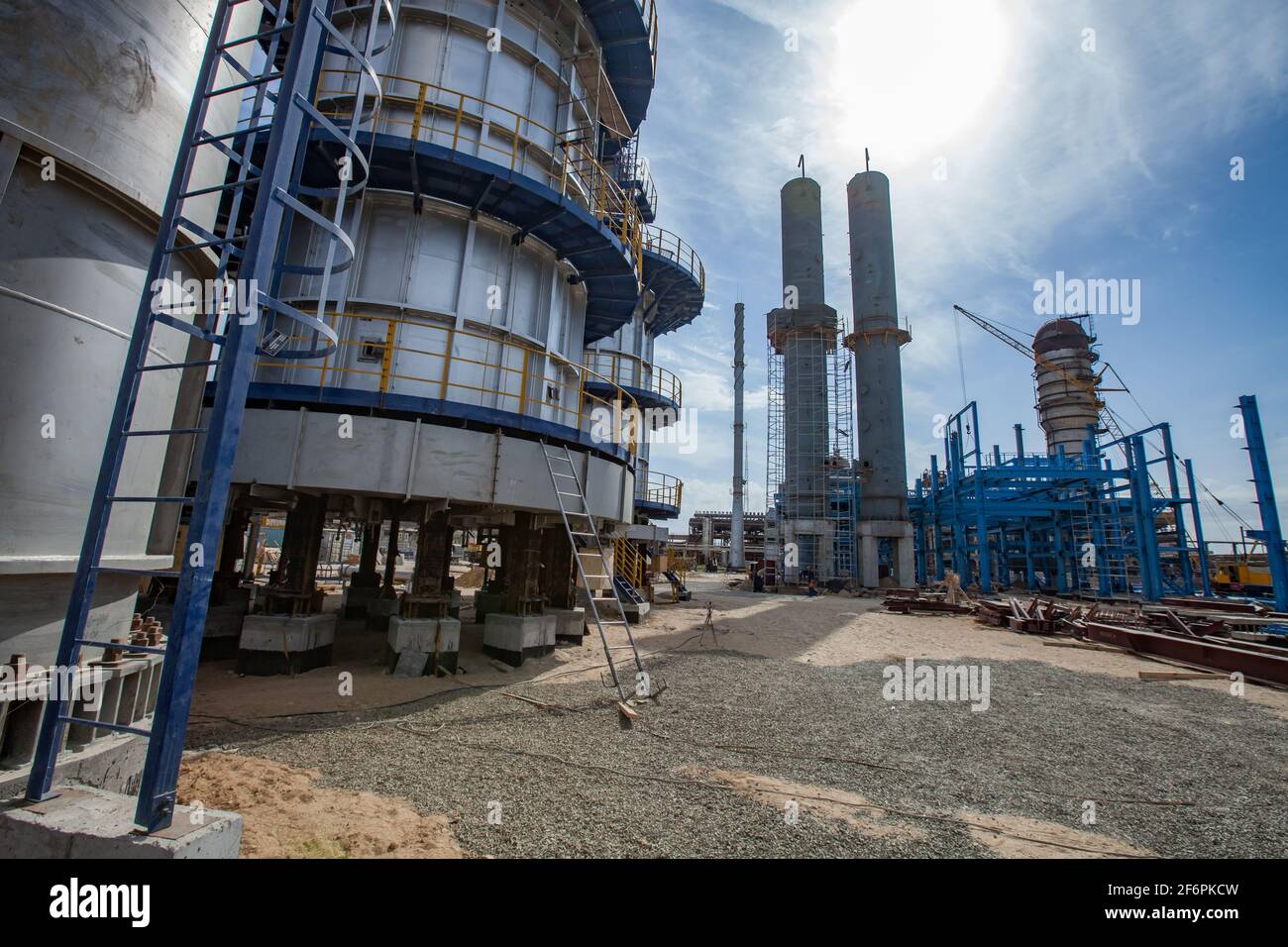 Aktau,Kazakhstan-May 19,2012: Construction of asphaltic bitumen plant. Refinery columns, smoke stack, mobile crane and blue steel building structure. Stock Photo