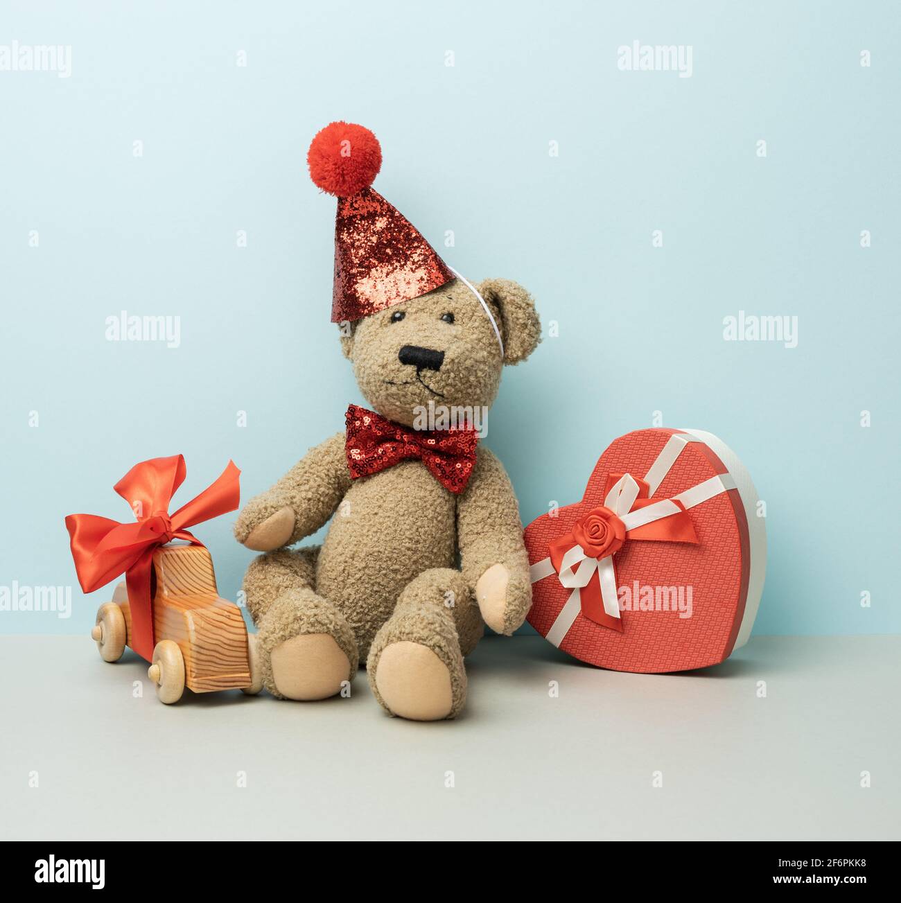 gift box and brown teddy bear in a red cap sits on a blue background ...