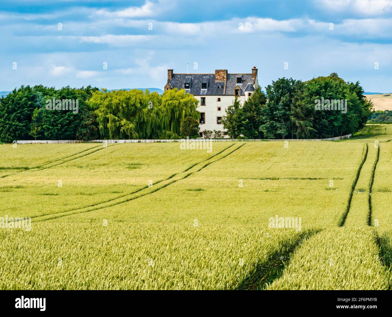 Ballencrieff Scots baronial style fortified house in wheat crop field in Summer agricultural landscape, East Lothian, Scotland, UK Stock Photo