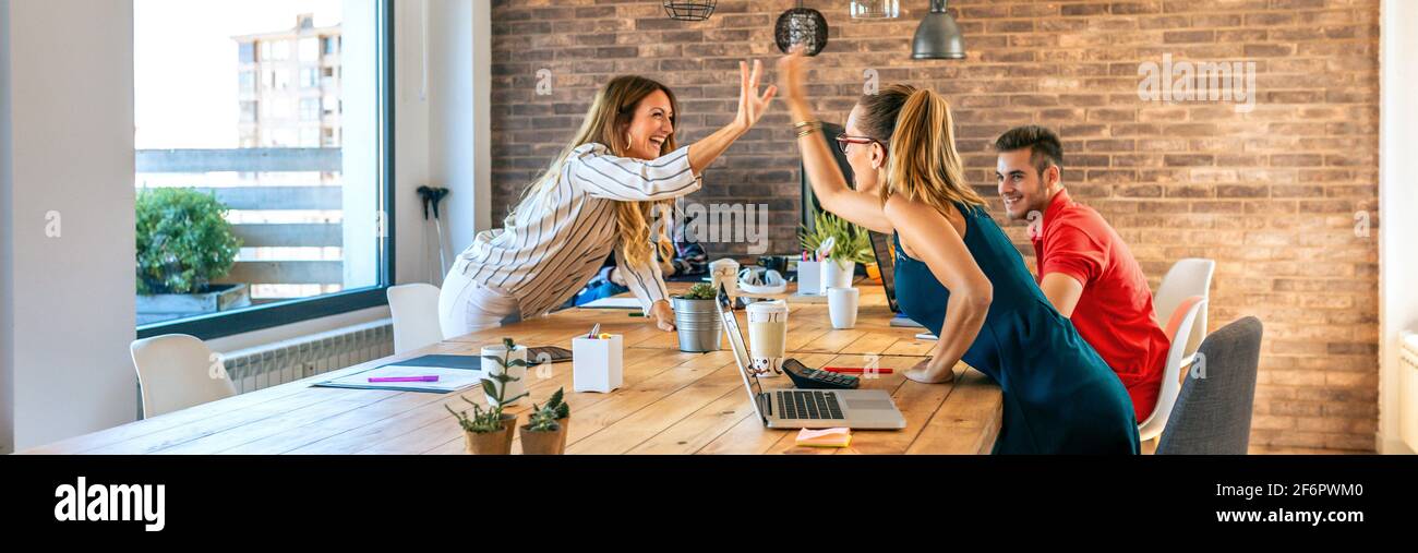 Business women celebrating a success high-fiving in the office Stock Photo