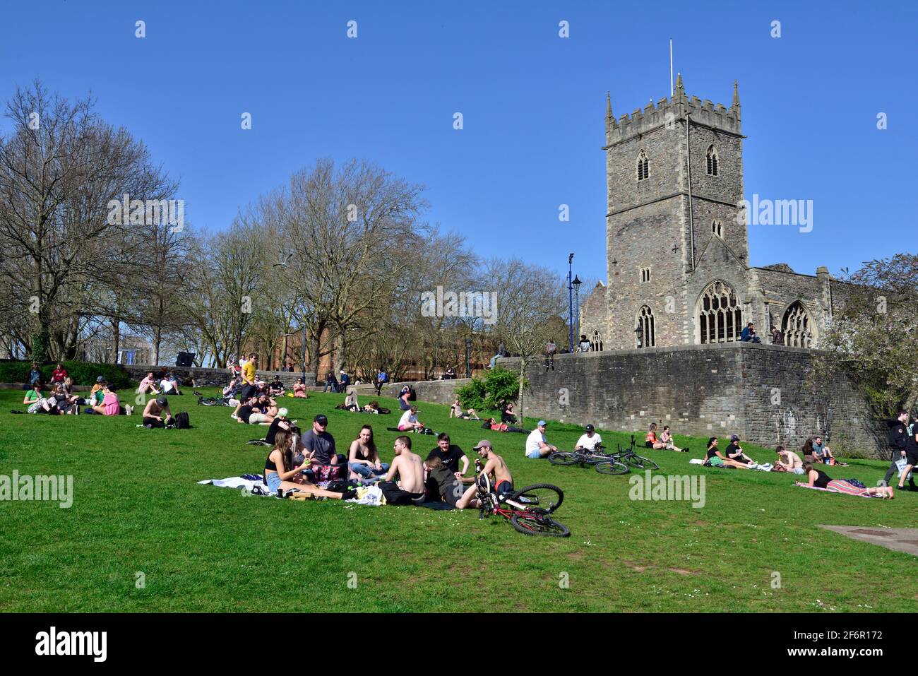 Groups of people enjoying the sunshine in Bristol Castle Park by St Peter's Church after coronavirus lockdown eased Stock Photo