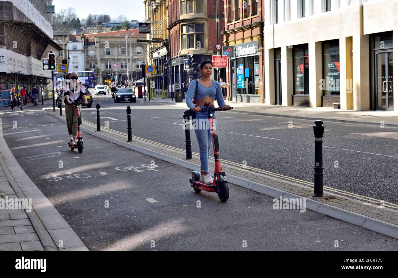 Young women riding on e-scooters in the centre of Bristol Stock Photo