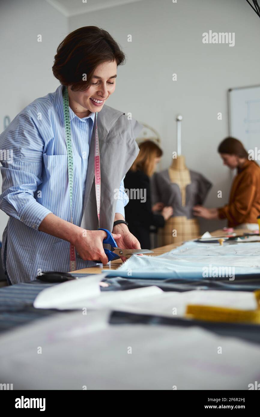 Dress designer cutting a fabric sheet with scissors Stock Photo