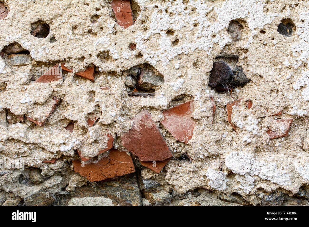 Old damaged dirty wall with cracks and wholes. Ruin facade made of natural stone and Bricks. A vintage background for design Stock Photo