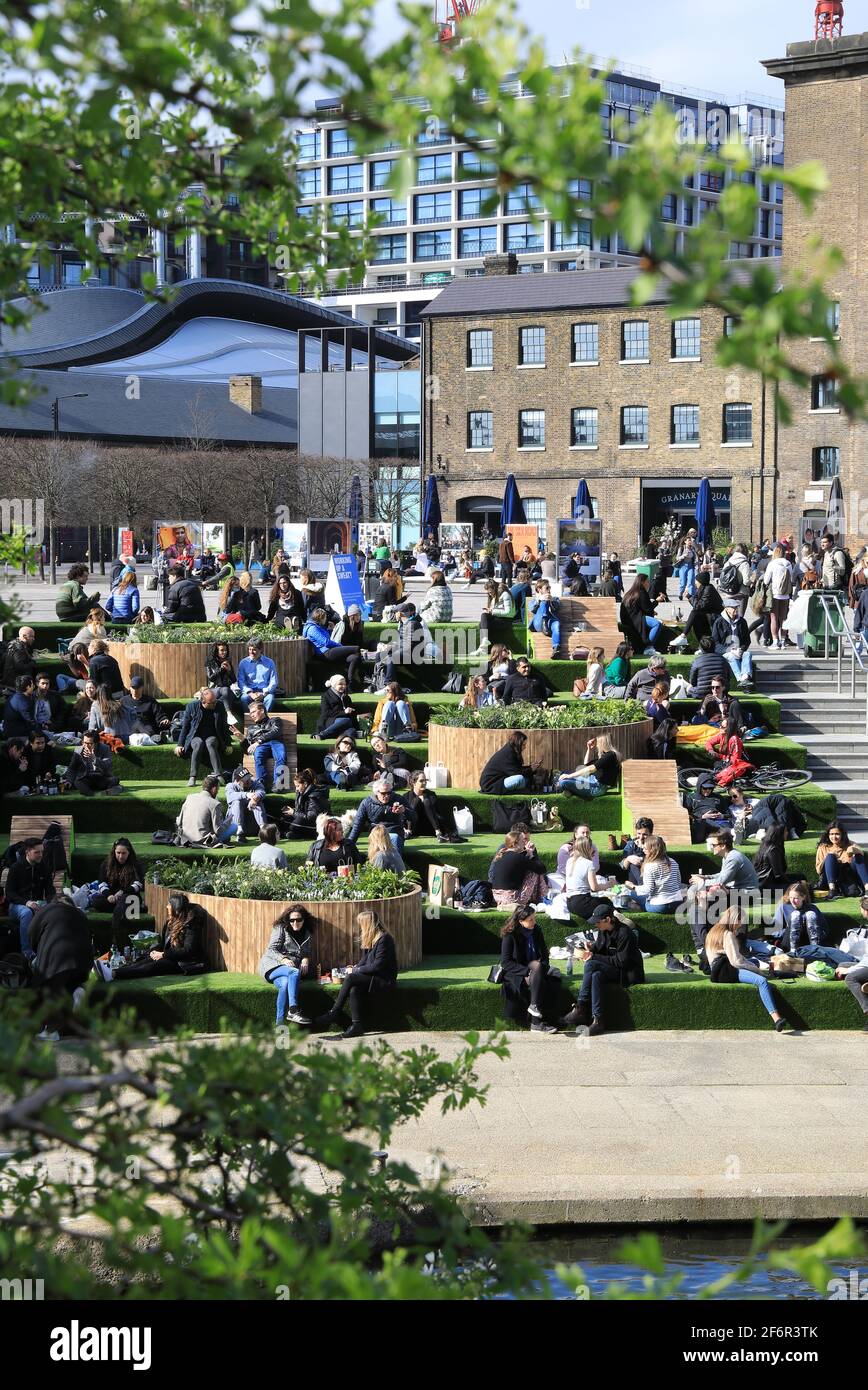 London, UK, April 2nd 2021. Despite the cool temperatures, the steps of Granary Square at Kings Cross were busy on Good Friday. The loosening of Covid restrictions on March 29th meant that groups of 6 or 2 households could socialize. Monica Wells/Alamy Live News Stock Photo