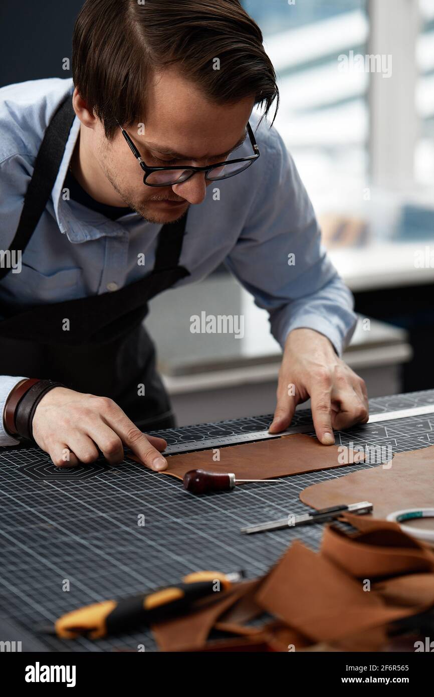 Skilled leather manufacture worker cutting some samples. Stock Photo