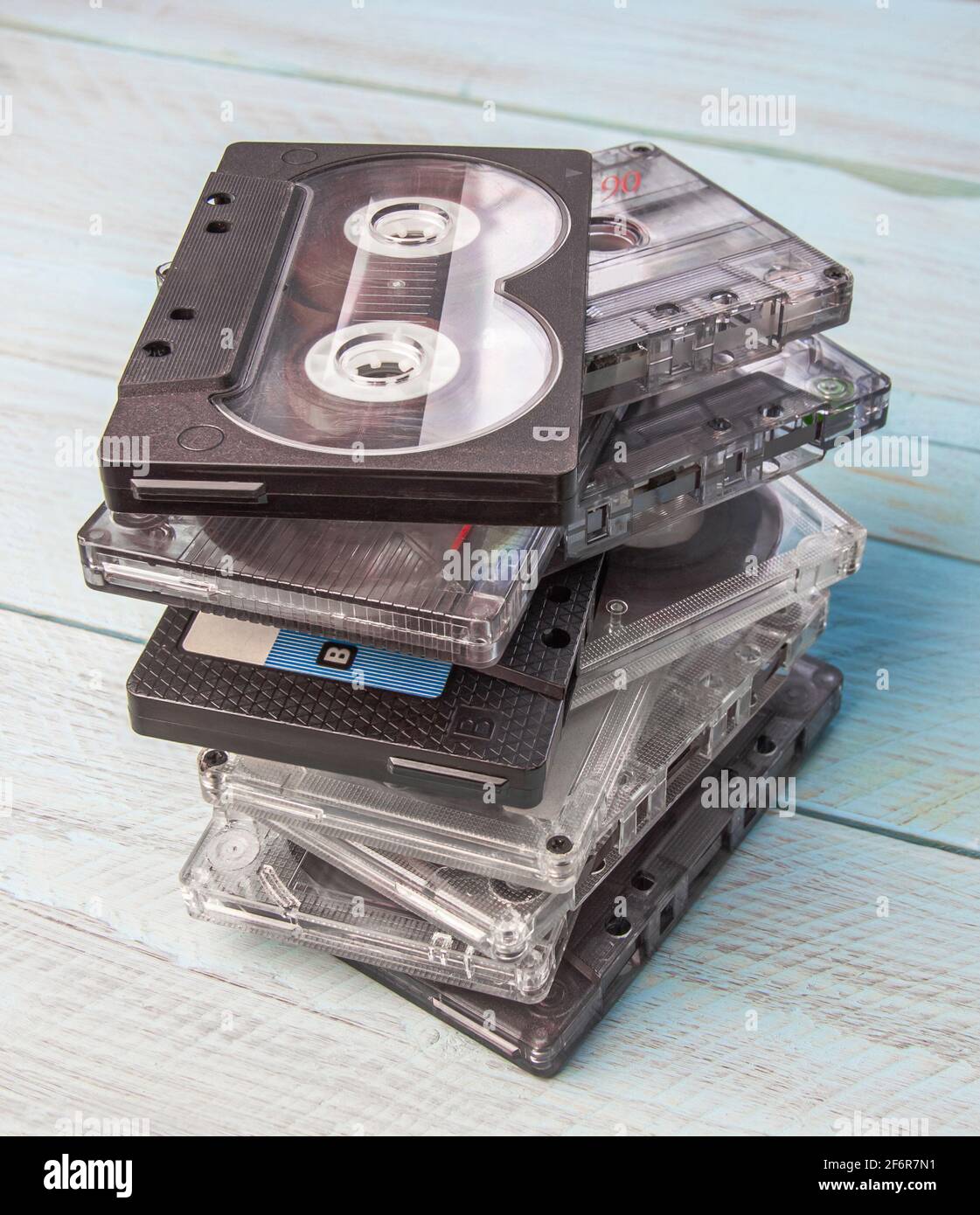 A careless stack of audio cassettes stands against a blue wooden background. Top view from the side. Vertical orientation.Close-up Stock Photo