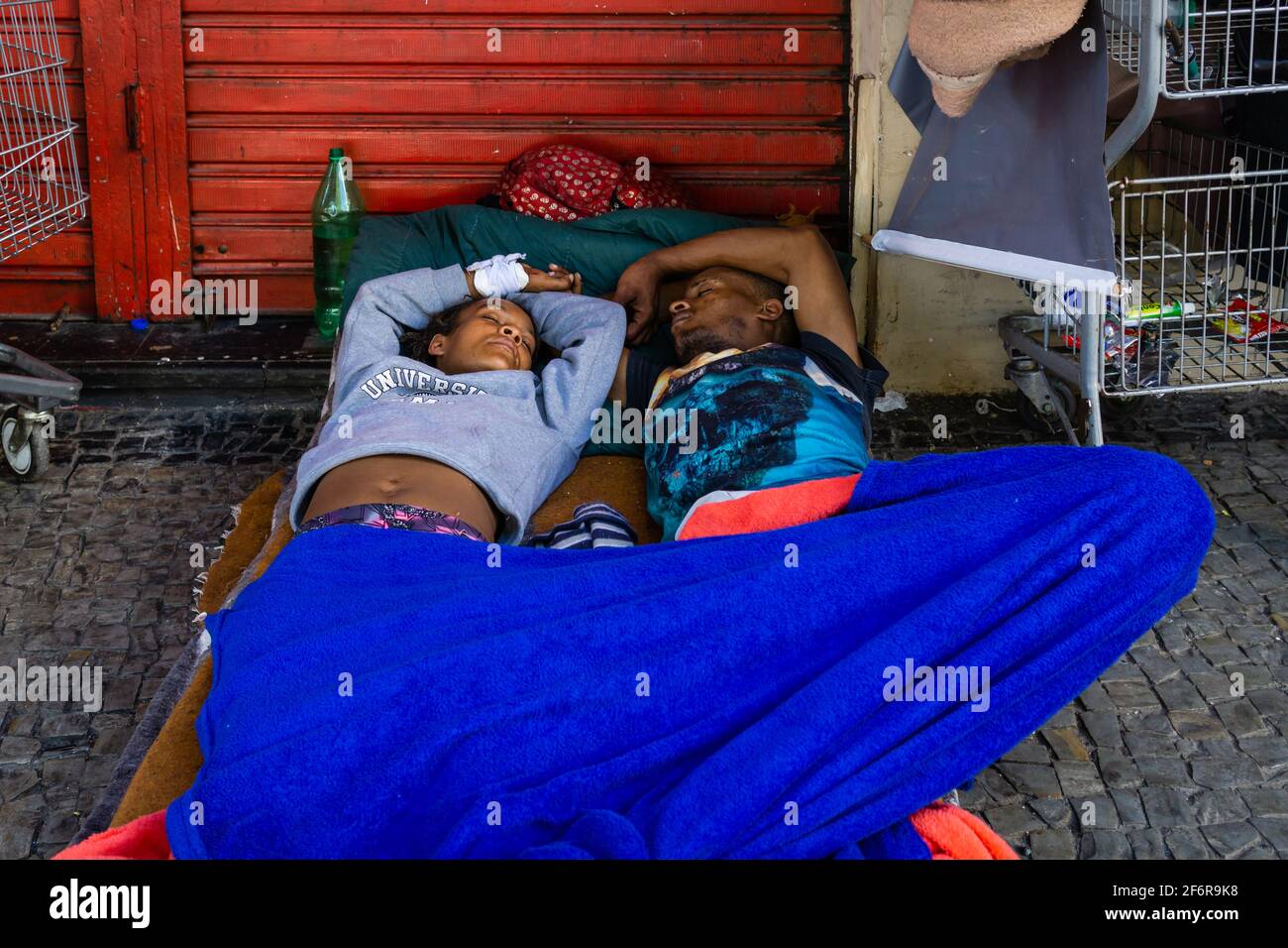 Brazilian homeless couple sleeping on the sidewalk of a street. Stock Photo