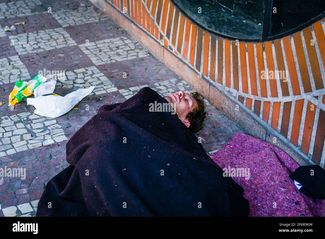 Brazilian young male homeless sleeping on the sidewalk of a street. Stock Photo
