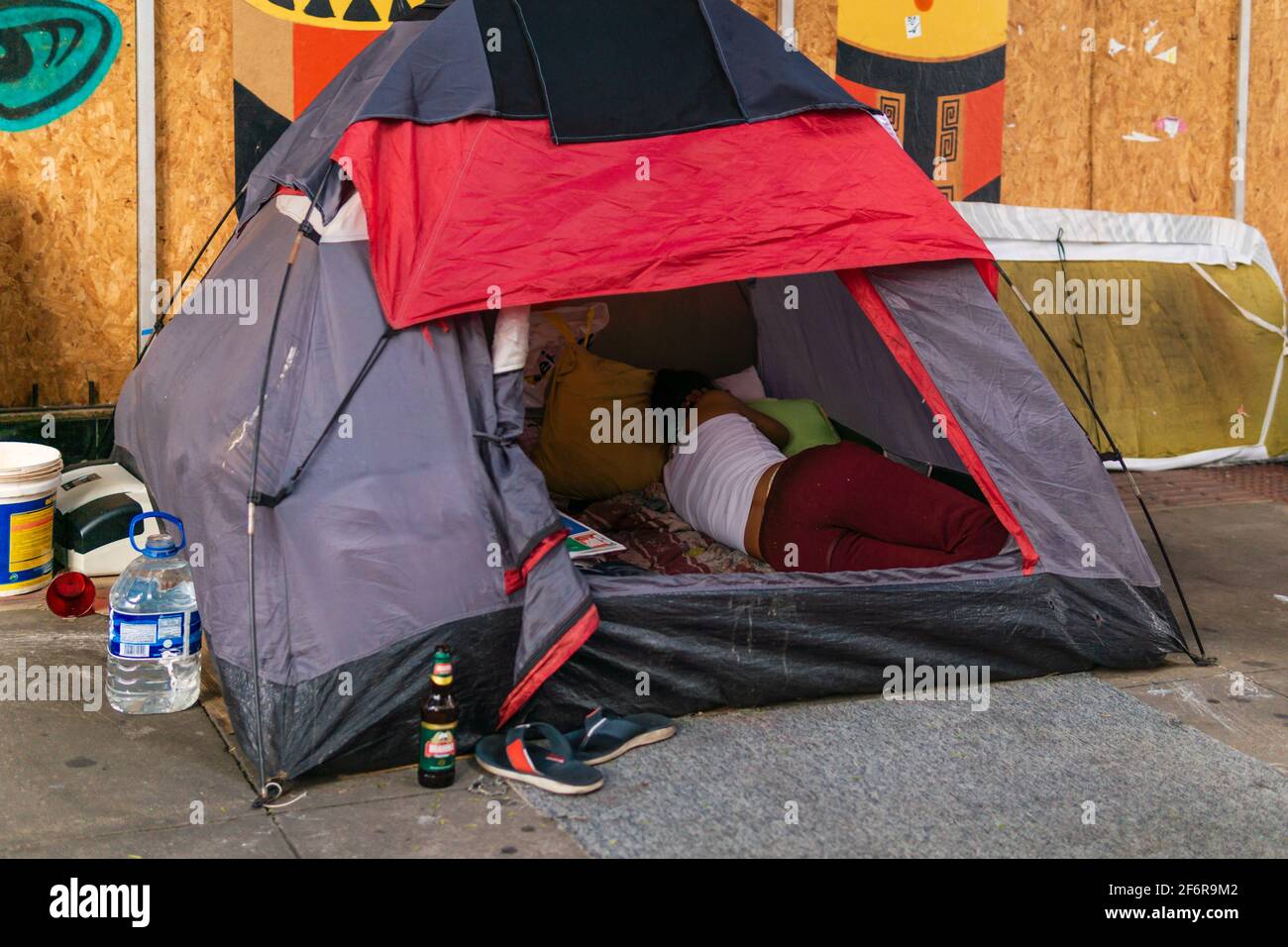Brazilian female homeless sleeping in a camping tent on the sidewalk of a street. Stock Photo