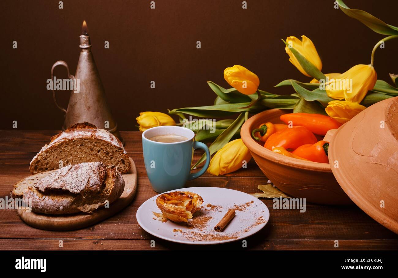 rustic table, with warm and cozy lighting shows cup with coffee, cinnamon, on the table you can also see peppers and a large ceramic bowl in raw color Stock Photo