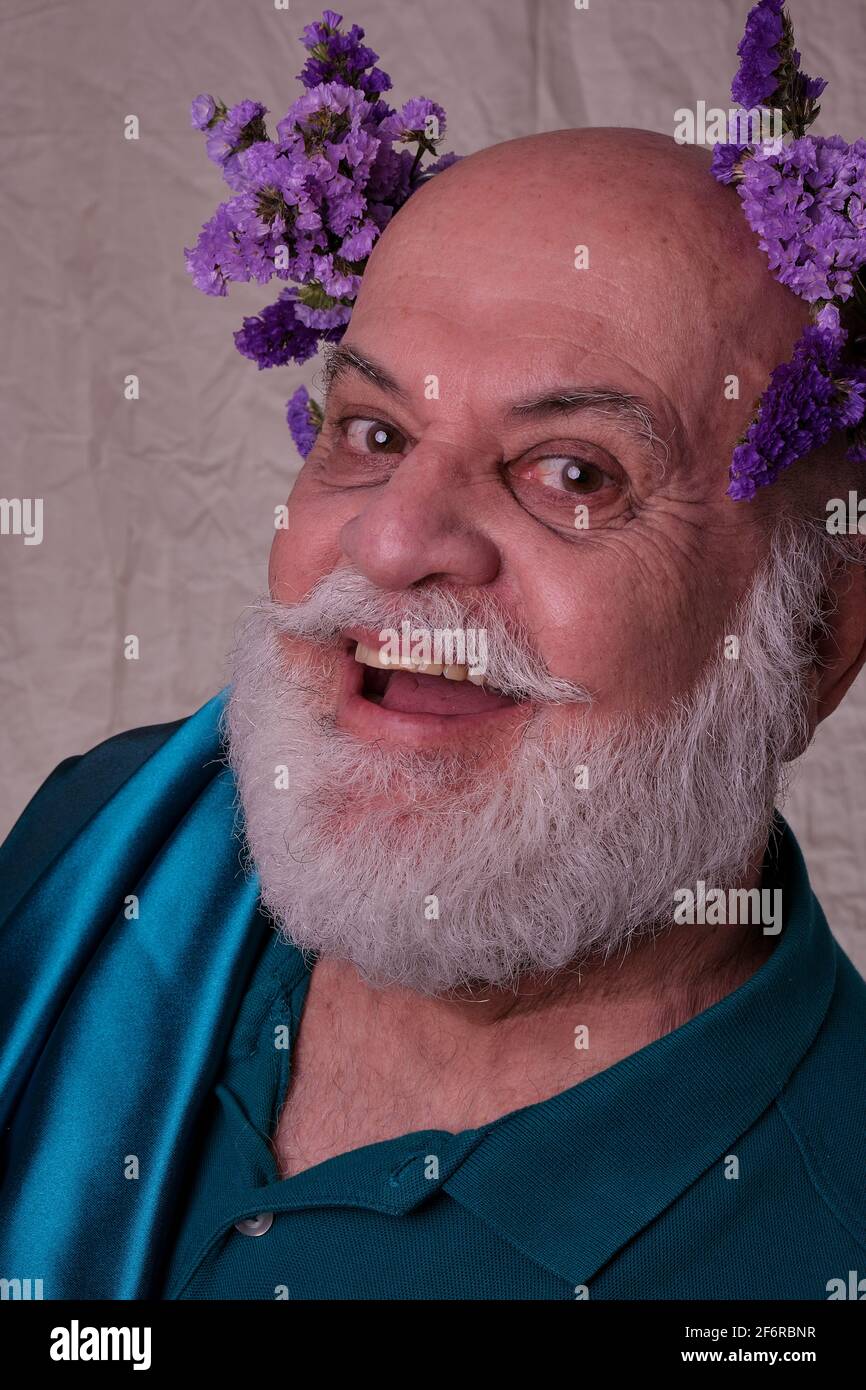 Elderly man, bald gray with purple flowers on his head, sympathetic and photogenic Stock Photo
