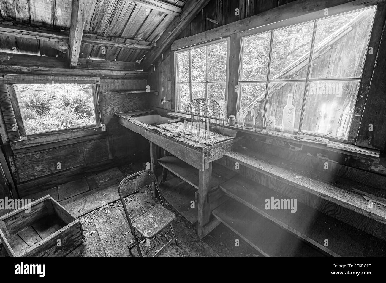 Black and white image of the interior of an abandoned cabin with sunrays. Stock Photo