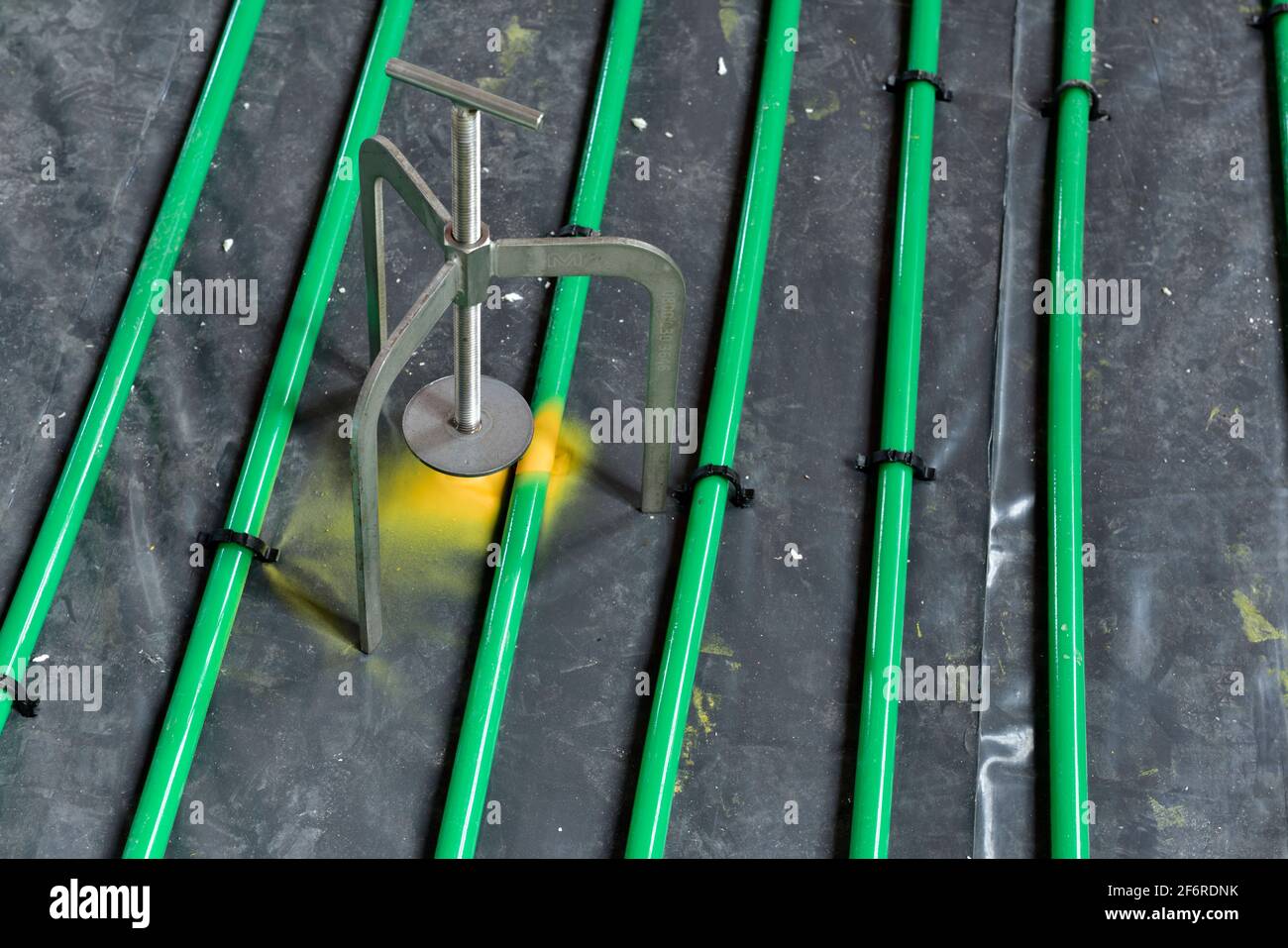 Green plastic underfloor heating pipes before being covered in poured