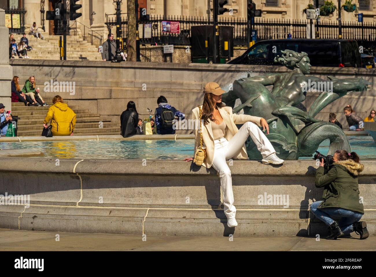 London, UK, 2 April 2021 Photographer with model on fountain in photo shoot. People enjoy sunshine in Trafalgar Square in the West End on Good Friday as coronavirus lockdown restrictions begin to be lifted.  Credit: JOHNNY ARMSTEAD/Alamy Live News Stock Photo
